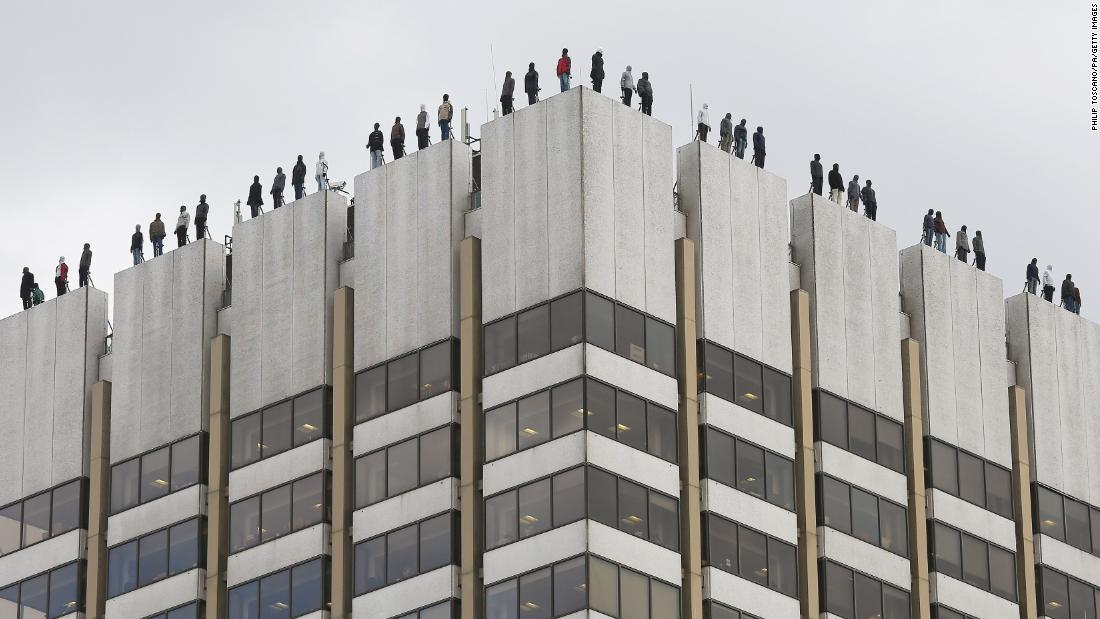 Here's why 84 male figures are standing on the edges of London rooftops