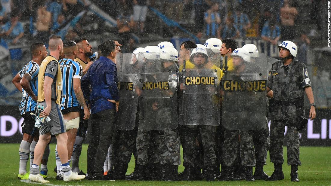 Riot police protect referee from players